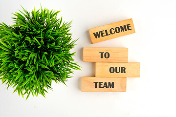 Concept words Welcome to our team on wooden blocks on a white background with a green plant out of...