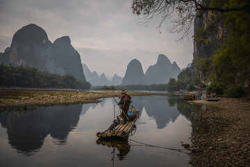 Cormorant fisherman and his bird on the Li River in Yangshuo, Guangxi, China. - obrazy, fototapety, plakaty