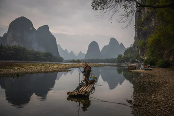 Selbstklebende Fototapete Guilin Cormorant fisherman and his bird on the Li River in Yangshuo, Guangxi, China.