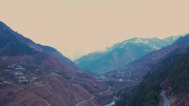 serene Kishan Ganga river in Dist Muzaffarabad, Azad Kashmir, framed by snow-capped mountains. Neelum Valley road and villages dot the landscape