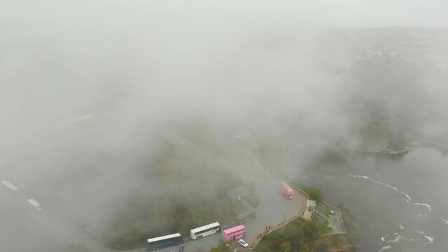 Aerial shot traveling through the clouds towards a neighborhood on a cloudy day.