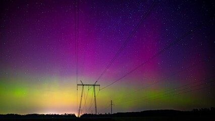 Glowing northern lights aurora borealis with transmission tower line in the foreground - time lapse - Powered by Adobe