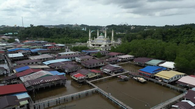 aerial drone shot over the floating villages of Kampong Ayer in Bandar Seri Bagawan in Brunei Darussalam towards a towering mosque

