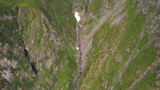 Valea rea in the fagaras mountains with rugged terrain and trails, during daylight, aerial view