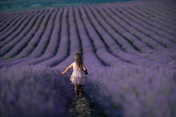 Lavender field girl. Back view happy girl in pink dress with flowing hair runs through a lilac field of lavender. Aromatherapy travel