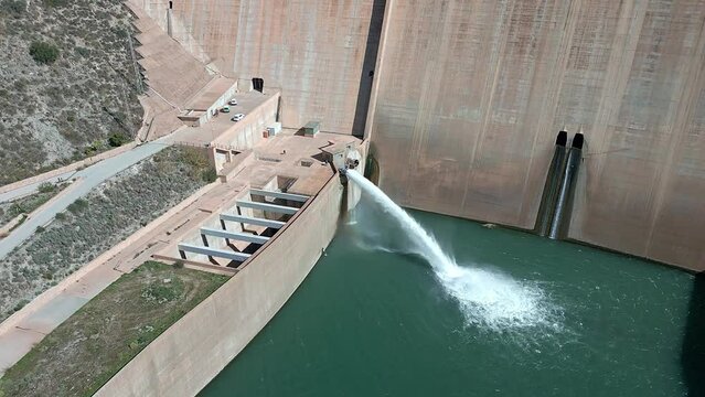 Hydroelectric satation. Gravity dam discharging water. Howell bunger valve in operation.  Dolly out aerial view view over the dam and river. Renewable energies.