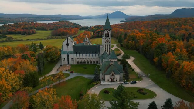 aerial over saint benoit du lac abbey and memprhemagog lake with mountains in the background at autumn season, magog, quebec region, canada during fall