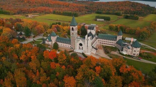 aerial shot around saint benoit du lac abbey at fall with colorful trees near magog on and memphremagog lake in quebec region, autumn season, canada