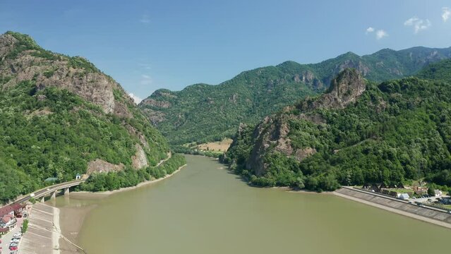 Aerial shot of Olt River flowing through the scenic Cozia Mountains, lush greenery surrounding