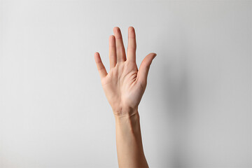 Woman showing five fingers on light background, closeup. Sign language