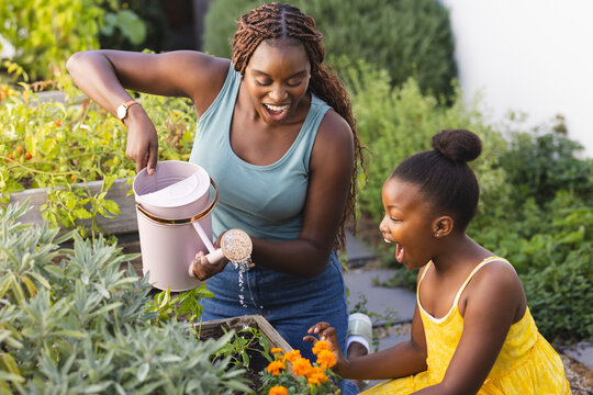 A young African American woman and a child are tending to a garden at home