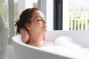 Young woman enjoys a relaxing bath at home, eyes closed