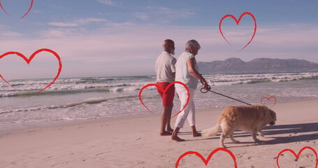 Image of hearts over senior african american couple with dog on sunny beach