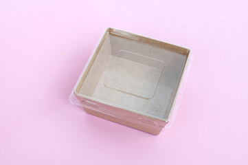 Transparent plastic and cardboard food container on a pink background.