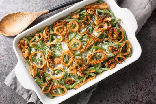 Green Bean Casserole With Cheesy Mushroom Sauce And Topped With Crispy Onions Close-up In A Baking Dish On The Table. Horizontal Top View From Above