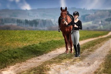 Foto op Canvas Rider and horse stand side by side on a path in a wide spring landscape. © RD-Fotografie