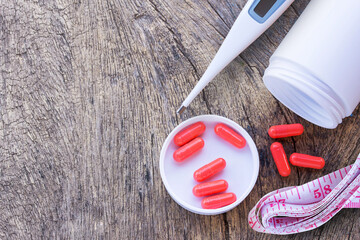 Closeup of medical capsule, pill or drug with thermometer and measuring tape