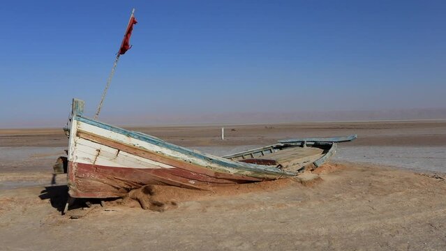 Abandoned boat on the salt flats of Chott el Jerid, Tunisia under clear blue sky