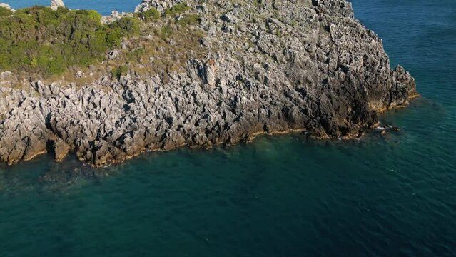 Aerial dolly above sharp jagged cape in Corfu Greece to reveal blue ocean water