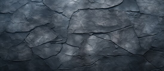 A close up of a grey cracked stone wall with a pattern of tints and shades, resembling monochrome...