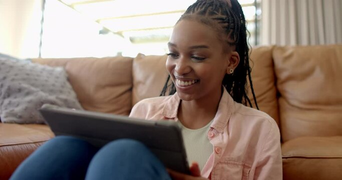 A young African American woman is using a tablet at home