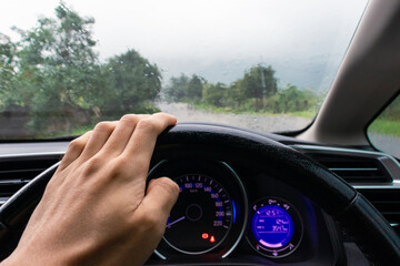 Travel concept. Man's hand inside a car on a rainy day with nature background. After some edits.