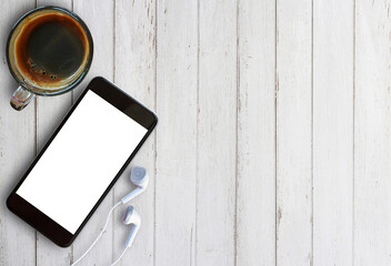 Smart phone and earphone with cup of coffee on old wooden table