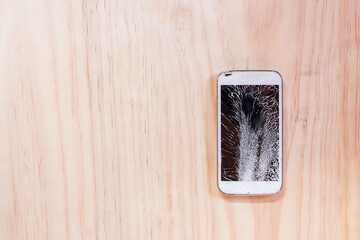 Smartphone with broken screen on wooden table