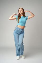 Young woman in blue T-shirt posing to camera on gray background