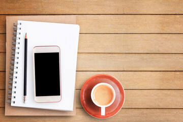 Empty blank paper notebook and smart phone on brown wooden table