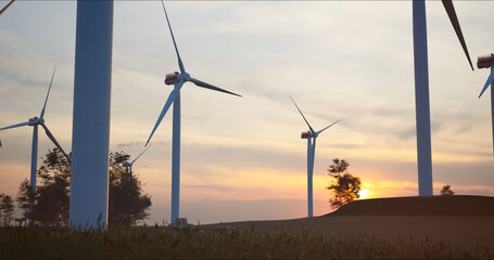 close-up camera moves along the blades of huge wind turbines against low sun. Green and renewable energy concept.