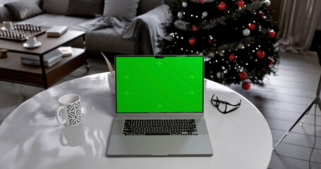 Laptop place on living room table, Christmas and New Year mood, Green screen display, Close up monitor of notebook with mock up
