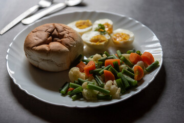 Close up of healthy breakfast food bread, eggs and boiled vegetables on a plate. Selective focus.