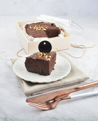 premium freshly baked dark cocoa chocolate brownie gold flower and earl grey peanut round birthday cake with walnut in wood bento box on white marble halal food sweet dessert menu for pastry cafe shop