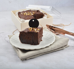 premium freshly baked dark cocoa chocolate brownie gold flower and earl grey peanut round birthday cake with walnut in wood bento box on white marble halal food sweet dessert menu for pastry cafe shop