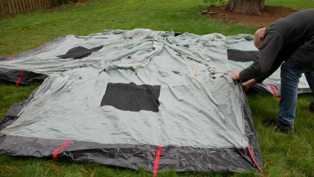 Two men pitching a tent on the grass at a campsite whilst camping