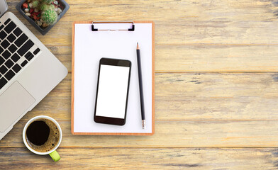 Office desk table with laptop computer,clipbroad,smart phone, cup of coffee and cactus.