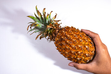 one fresh yellow pineapple, held in the lower right handI