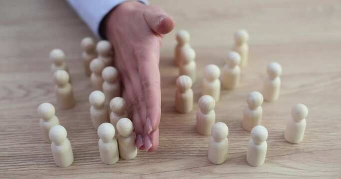 Female hand separates groups of white wooden figures on table