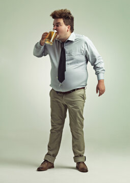 Man, face and drinking with beer for party or chug in obesity on a studio background. Young male person or plus size model with glass, mug or alcohol in satisfaction for brew or booze on mockup space