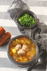 Meatball in a spoon. soup with meatballs in a black bowl and croutons in hard light. A European dish typical of Spain, Sweden, Turkey, and Russia. Top view, flat lay