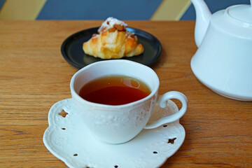 Cup of Hot Tea with a Plate of Almond Croissant in the Backdrop