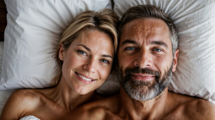 A man and a woman lying comfortably, with a satisfied face, next to each other on a bed, facing each other.
