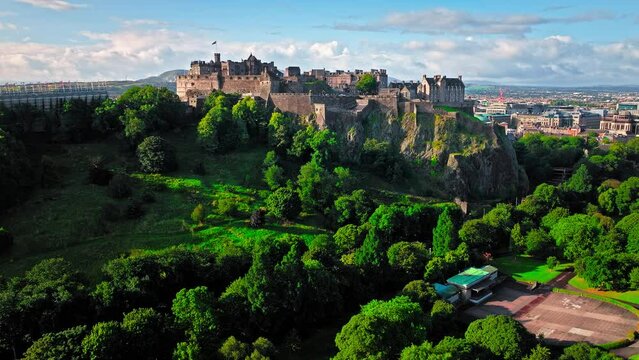 Aerial view of Edinburgh Castle with green gardens in Scotland. Historic castle and barracks housing the Crown Jewels and National War Museum of Scotland stands on Castle Rock.
