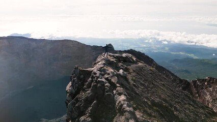 A man conquered Agung volcano, stands happy at the top and rejoices at the achievement of the goal.