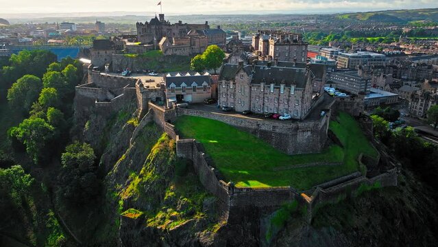 Aerial view of Edinburgh Castle with green gardens in Scotland. Historic castle and barracks housing the Crown Jewels and National War Museum of Scotland stands on Castle Rock.
