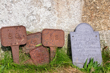 Alte Feldnummern neben Anime Grabstein an der Wand einer Kirche in Cornwall 