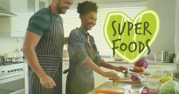 Animation of super foods text over diverse couple preparing healthy meal in kitchen