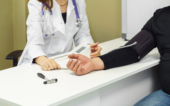 Pressure measurement. Female doctor examining male patient, measuring blood pressure at hospital
