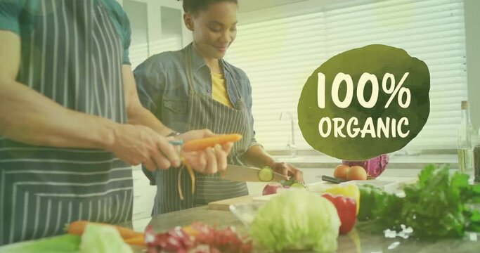 Animation of 100 percent organic text over diverse couple preparing healthy meal in kitchen